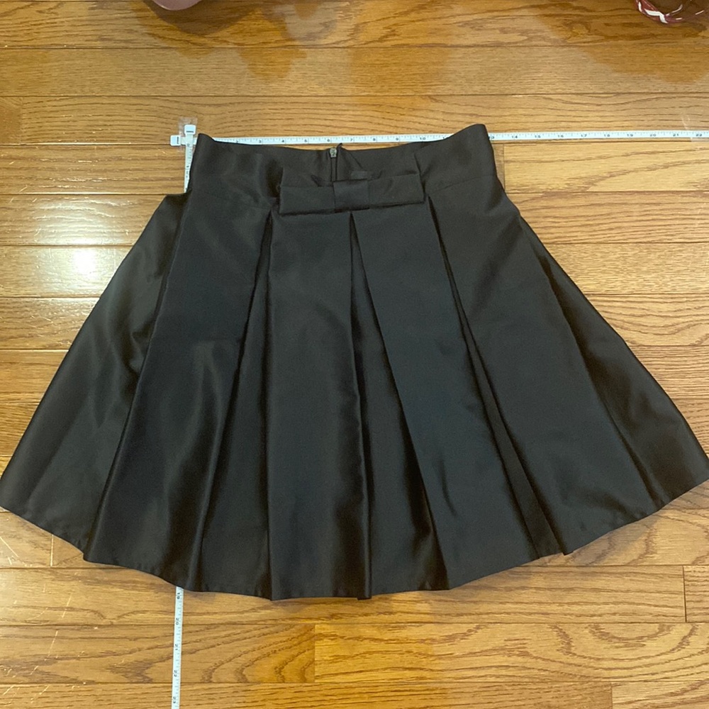 Adorable pleated, satiny, mini skirt with bow detail